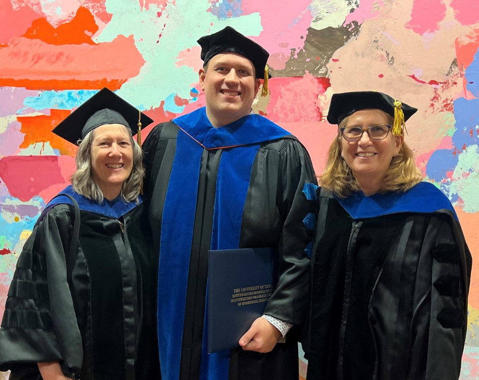 A man and two women, all in academic regalia